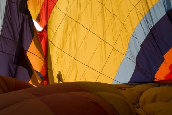 La silueta de un hombre junto a un globo aerostático que se infla lentamente para preparar una inolvidable vuelo en globo aerostático.