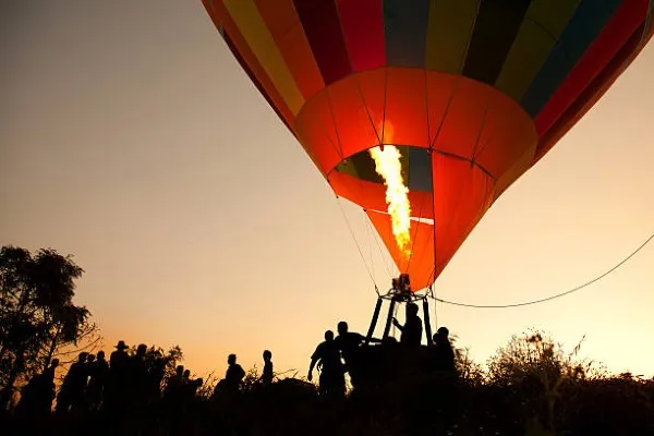 Globo aerostático elevándose sobre el horizonte durante un amanecer despejado, momento ideal para vivir la emoción de un paseo en globo inolvidable y tranquilo.