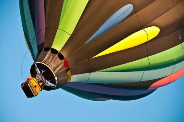 Globo aerostático en pleno vuelo sobre un paisaje despejado, ofreciendo una vista espectacular desde las alturas durante un paseo en globo lleno de tranquilidad y emoción.