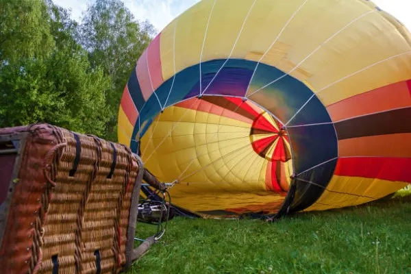 Globo aerostático despegando suavemente desde tierra firme, momento inicial que marca el comienzo de un emocionante paseo en globo lleno de expectativa y belleza natural.