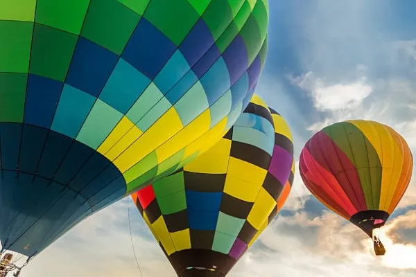 Tres globos con pasajeros impulsandose a los cielos para que las personas disfruten de un paseo en globo aerostático por Teotihuacan.