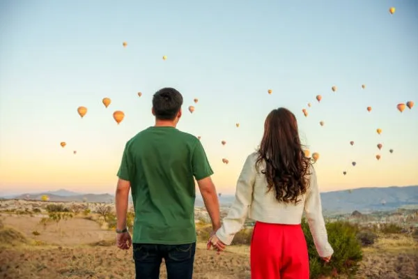 Pareja tomada de la mano esperando su turno para disfrutar de los mejores paseos en globo México por el valle de Teotihuacan