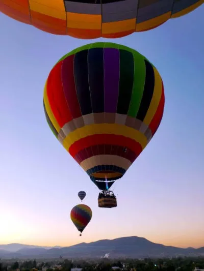 Personas disfrutando de un vuelo en globo aerostático sobre las pirámides de Teotihuacan. Lugar donde se vive un viaje inolvidable con acompañantes.