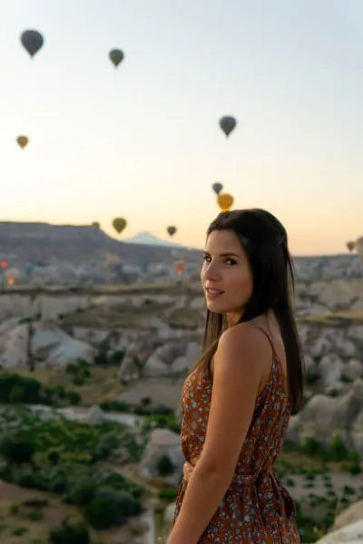 Mujer posando para una fotografía, con varios globos aerostáticos detrás, como recuerdo del viaje inolvidable que vivió en Teotihuacan.