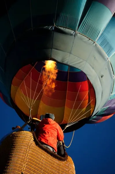 Persona con chamarra anaranjada disfrutando de las increíbles vistas que ofrecen los viajes en globo aerostático,