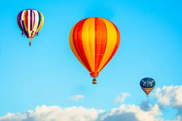 Viajes en globo aerostático de diferentes colores y sobre un cielo despejado en su máximo color azul.