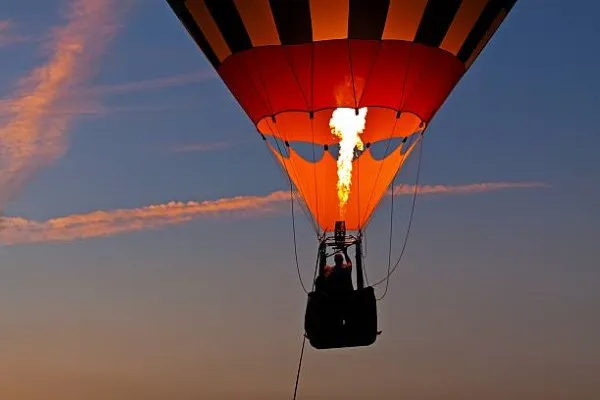 Globo aerostático despegando con cielo despejado al fondo, representando la tranquilidad y belleza de un paseo que garantiza un vuelo seguro.