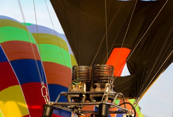 Vista cercana de un globo aerostático inflándose antes del despegue, preparado por profesionales que aseguran siempre un vuelo seguro y controlado.