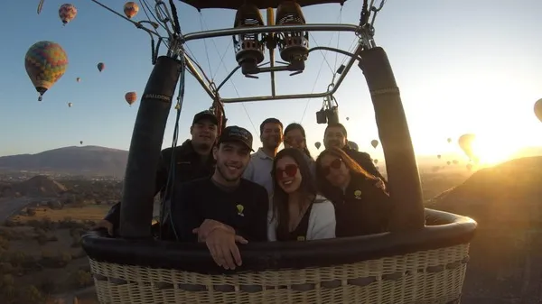 Grupo de amigos disfrutando de un amanecer en globo aerostático sobre las pirámides de Teotihuacan.