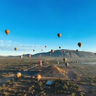 Personas gozando de un maravilloso atardecer en teotihuacan en globo aerostático disfrutando de la vista panorámica de la pirámides del sol y la luna