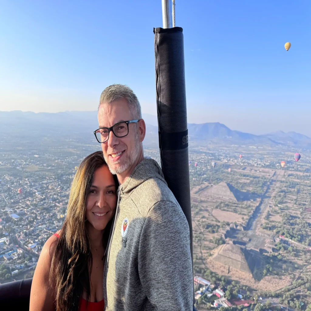 A happy couple embraces mid-air during their balloon ride Mexico City, enjoying the scenic sunrise and romantic atmosphere together.