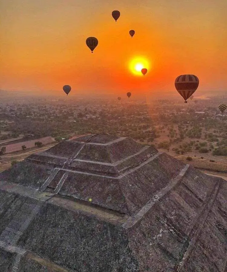 Multiple colorful balloons float gracefully over the Pyramid of the Sun during a breathtaking Teotihuacan hot air balloon tour.