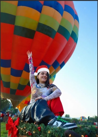 Joven tomándose una selfie durante sus vuelos en globo para navidad, con el cielo iluminado y ambiente festivo navideño.