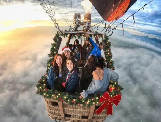 Grupo de amigos disfrutando vuelos en globo para navidad con canastilla decorada con luces y escarcha.