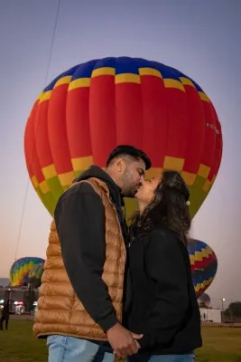 Smiling couple posing during a hot air balloon ride during Easter with a spectacular landscape.