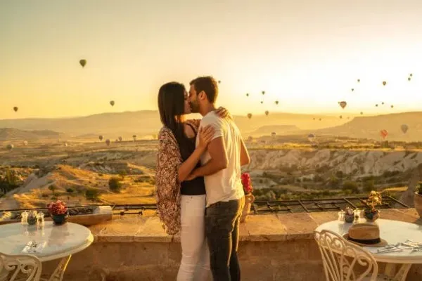 A couple enjoying a romantic meal with hot air balloons in the background during a sunrise hot air balloon ride for two.