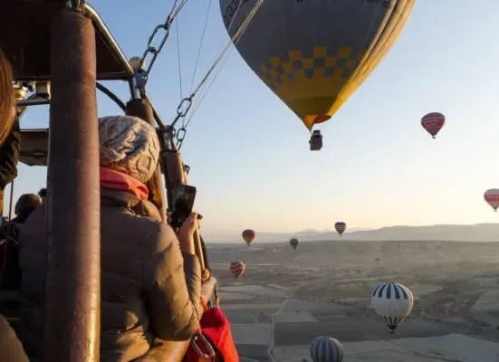 Woman enjoying the sunrise scenery during a hot air balloon ride for two with a breathtaking and relaxing panoramic view.