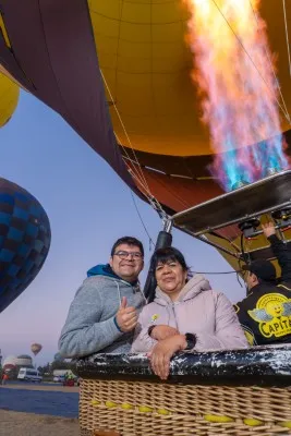 Pareja disfrutando la experiencia mientras descubren por qué vuelan los globos aerostáticos en un ambiente al amanecer.