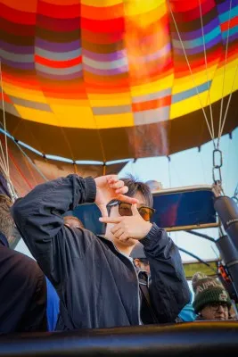 Joven posando sonriente dentro de un globo mientras observa las partes de globo aerostático antes del vuelo.