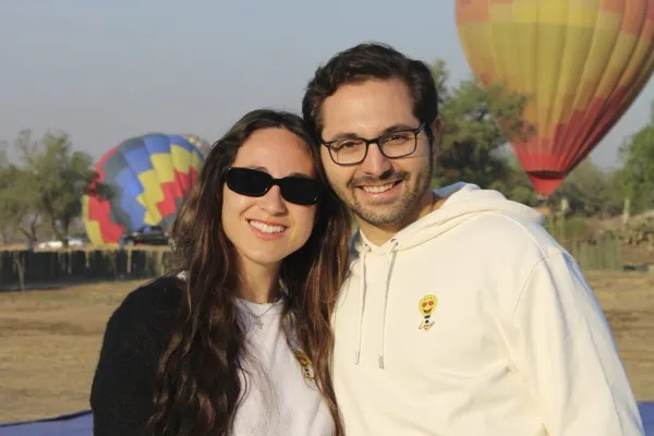 Pareja joven sonriente preparándose para despegar en sus vuelos en globo en Teotihuacán.