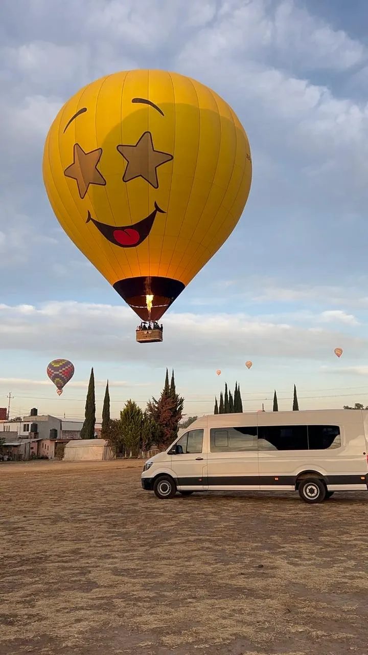 Camioneta blanca traslada pasajeros para vuelo en globo desde CDMX con transporte rumbo al globopuerto de Teotihuacán.
