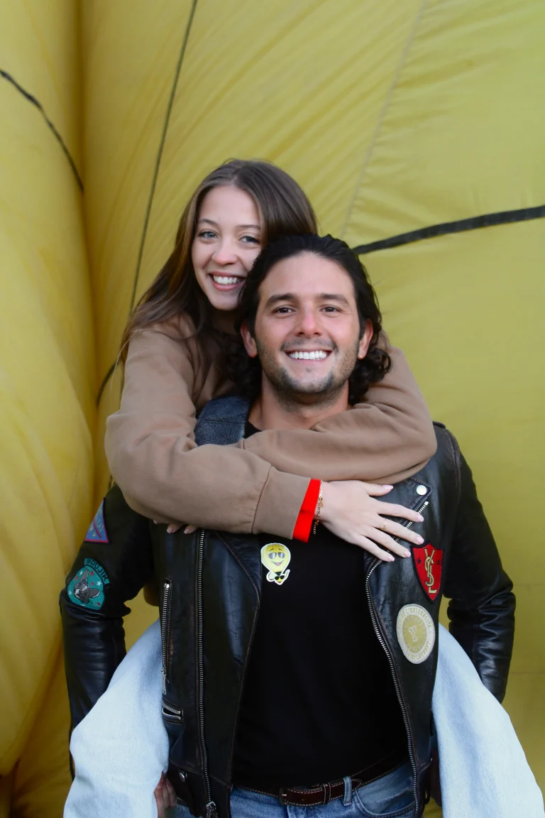 Pareja sonriente disfruta de un vuelo en globo desde CDMX con transporte incluido para un amanecer romántico sobre paisajes impresionantes en Teotihuacán.