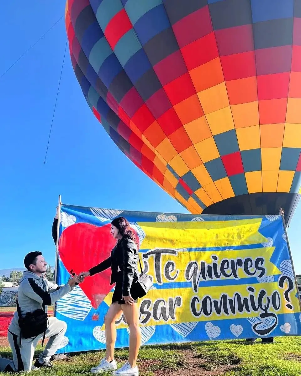 Hombre proponiendo matrimonio con pancarta romántica para pedir matrimonio en globo aerostático Teotihuacán a su prometida.