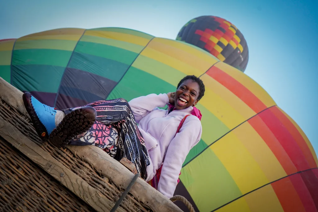 Woman poses sitting in the basket, showing what to expect during your hot air balloon flight in Teotihuacán.