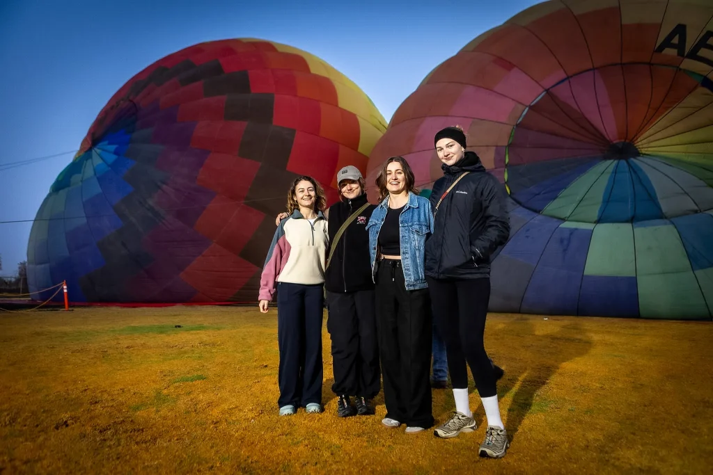 A smiling family watches the sunrise before takeoff, showing what to expect during your hot air balloon flight in Teotihuacán