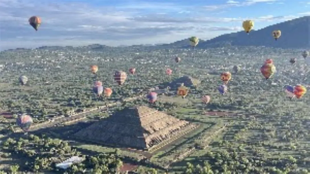 Vista aérea de varios globos aerostáticos al volar en globo mientras recorren el valle de Teotihuacán al amanecer.