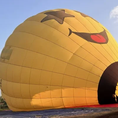 Globo aerostático amarillo en el suelo mientras revisan las partes de globo aerostático antes del despegue.
